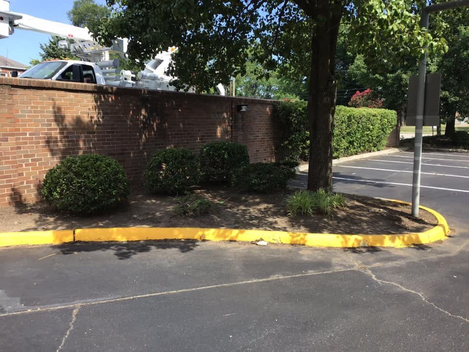 A parking lot with a yellow curb and a brick wall