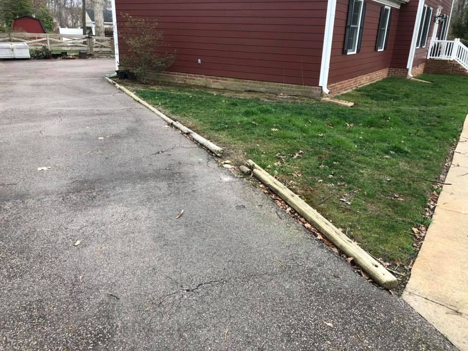 A driveway with a wooden curb in front of a house.