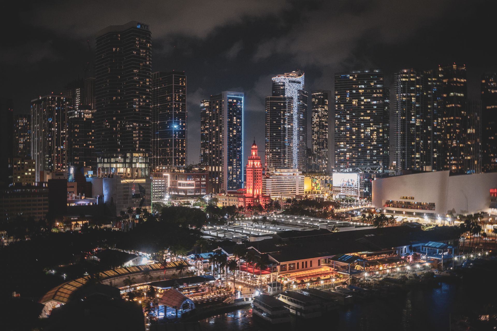 Nighttime city skyline with illuminated skyscrapers and a brightly lit waterfront below