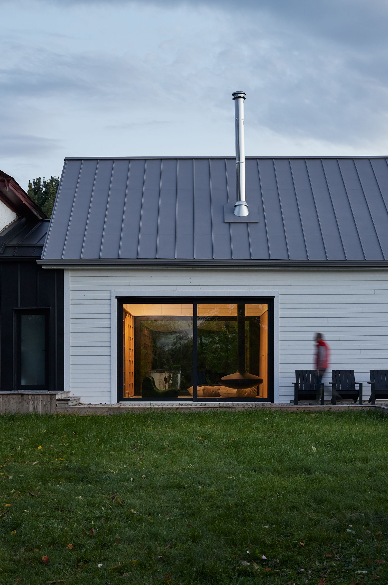 Une maison blanche avec un toit gris et une grande fenêtre