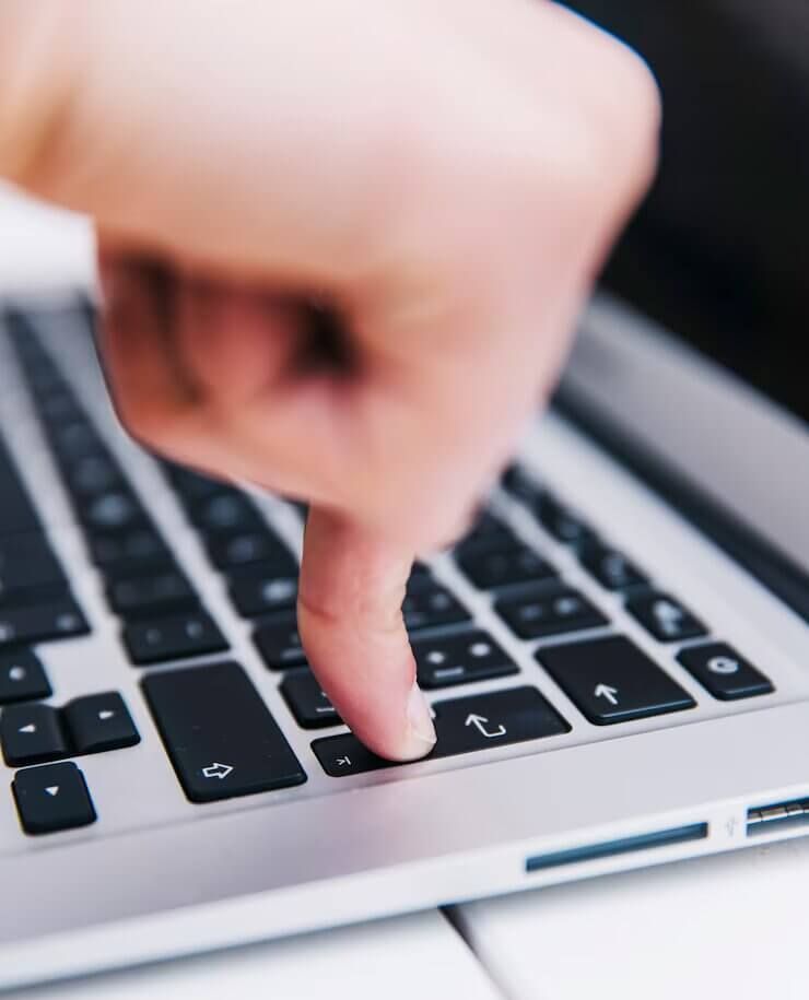 Una persona está escribiendo en una computadora portátil con el dedo en la tecla Enter.