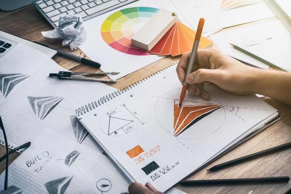 A Person Is Drawing a Triangle in A Notebook with A Pencil — Signmax Bundaberg In Kensington, QLD
