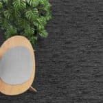 Top-down view of a tan chair beside green plants on a dark textured carpet.