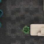 Overhead view of a dark carpeted floor with a beige sofa and a small green plant.