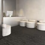 Modern minimalist lobby with white seating, light walls, and dark carpet flooring