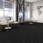 Modern office with desks, white chairs, and large windows on a dark carpeted floor