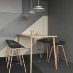 Modern dining nook with a light wood table, black chair, and two hanging pendant lights against gray walls