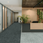 Modern office lobby with dark reception desk, potted plants, and glass-walled hallway
