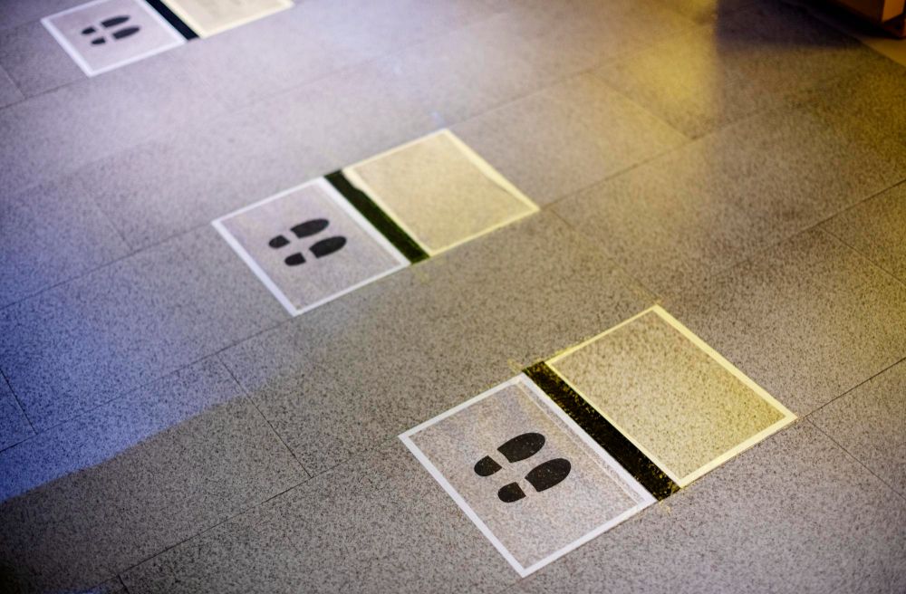 Floor tiles with small white squares, each marked with dark footprint icons, on a gray surface.