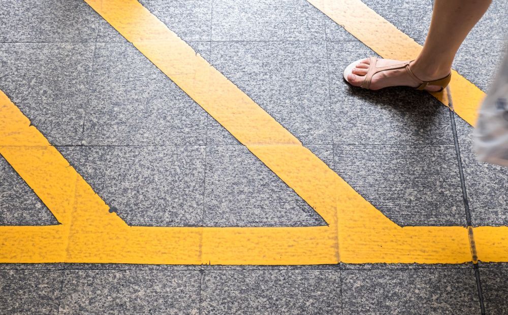 Bare feet stepping on a textured gray sidewalk with yellow painted lines