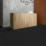 Wooden reception desk in a modern lobby with geometric wall decor and dark flooring