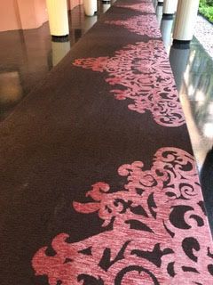 Pink floral-patterned carpet runner in a hallway with columns and glossy flooring