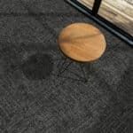 Dark carpeted floor with a round wooden stool or table leg and a black metal frame nearby.