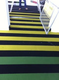 Stairway with black-and-yellow striped steps and a green landing, viewed from above