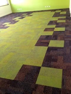 Empty room with green and dark purple patterned carpet and a lime green wall