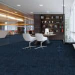 Modern office lounge with two white chairs, dark shelving, and blue carpeted floor
