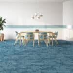 Bright dining room with white chairs, wooden table, and blue carpet in a minimalist interior.