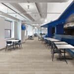 Empty modern office lounge with tables, chairs, and a blue booth seating area