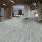 Empty modern office lobby with gray flooring, curved white walls, and open ceiling beams
