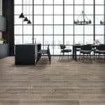 Empty modern lounge with large windows, black chairs, pendant lights, and wood flooring