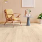 Minimal living room with a wooden chair, small round side table, and potted plant on a light floor