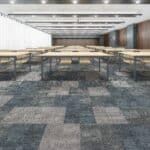 Empty modern conference room with long tables, patterned carpet, and recessed ceiling lights
