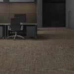 Empty office area with a desk, chair, and carpeted floor near a doorway.