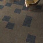 Carpeted floor with dark blue square patterns and the edge of a chair or table leg at top center