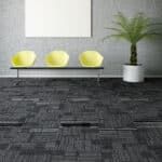 Modern office waiting area with three yellow chairs, a potted plant, and dark patterned carpet.