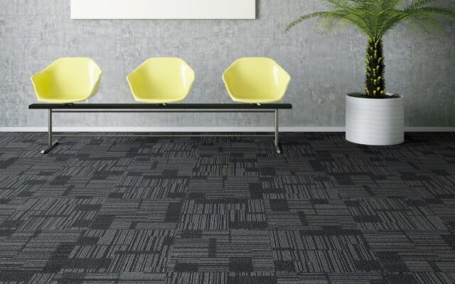 Waiting area with three yellow chairs, a potted plant, and patterned gray carpet.