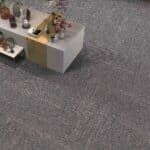 Small display table with assorted miniature items on a gray carpeted floor.
