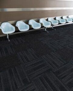 Row of pale blue chairs against a wall on a dark patterned carpet in a waiting area