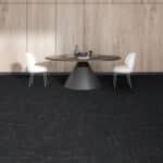 Modern dining area with a round table and two white chairs on a dark carpeted floor.