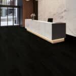 Modern white reception desk in a minimalist room with dark carpet and large windows