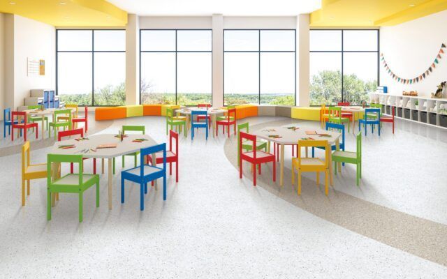 Bright, colorful classroom with small tables and chairs in a sunlit, empty learning space