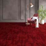 Modern living room with dark red carpet, gray cabinets, a chair, lamp, and potted plant.