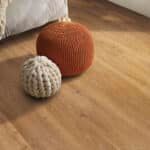 Two textured balls, one orange and one cream, on a wooden floor.