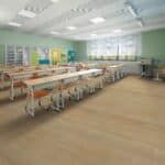 Bright classroom with long tables, colorful wall posters, and large windows.