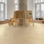 Bright loft interior with large windows, light wood furniture, and beige flooring