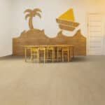 Warm-toned room with a wooden table, stools, wall mural of a palm tree and sailboat, and a staircase at right