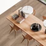 Top-down view of a wooden dining table with chairs, dishes, and a white round side table on a wood floor