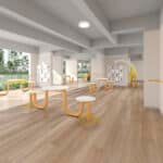 Bright modern kitchen with wooden stools, light wood floors, and large windows overlooking greenery