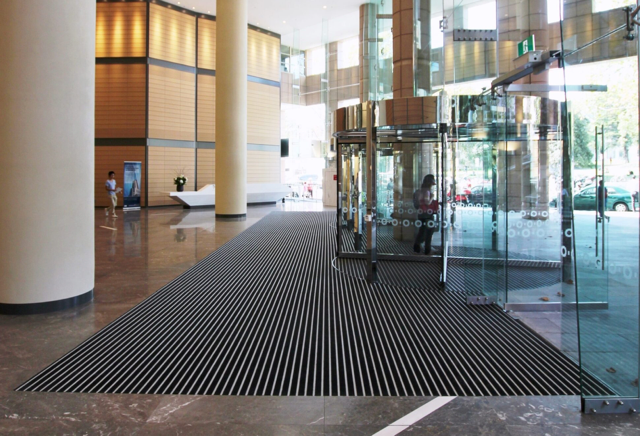 Rows of school cafeteria tables with attached swivel stools on a blue and white checkered floor.