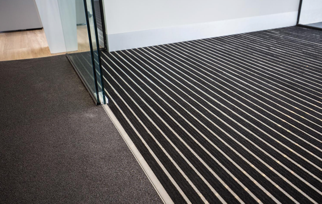 Office hallway with striped carpet and glass doorway transition mat