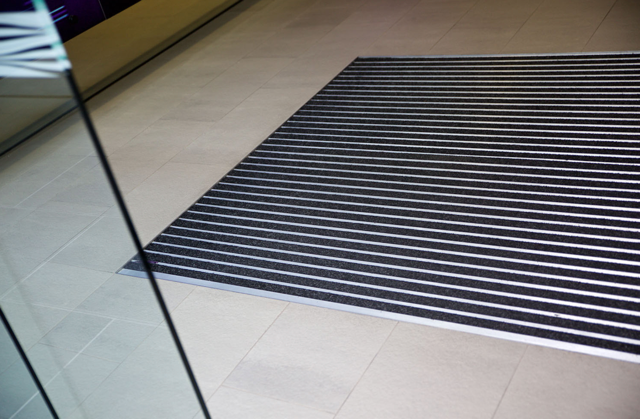 Black-and-white striped floor mat on beige tile near a glass door