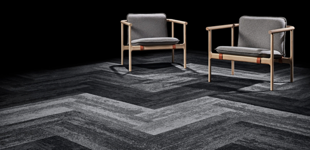 Two gray armchairs on a dark patterned carpet in a minimalist room
