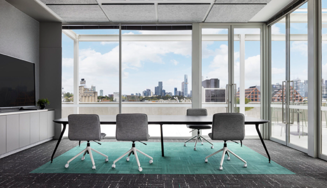 Modern conference room with large windows, four gray chairs, and a city skyline view