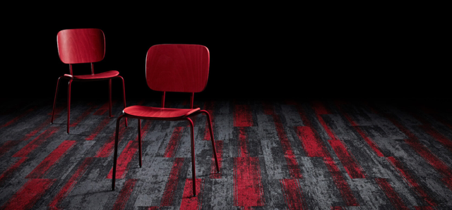 Two red chairs on a dark patterned stage floor with a black background