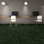 Two white chairs at a long desk in a gray room with a green carpet