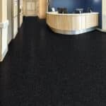 Lobby with curved light wood reception desk and dark carpeted floor.
